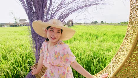 Portrait-of-Asian-adult-woman-relaxing-near-big-rice-field