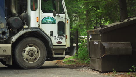 Side-view-of-white-garbage-truck-picking-up-garbage-bin-from-neighborhoods---close-up