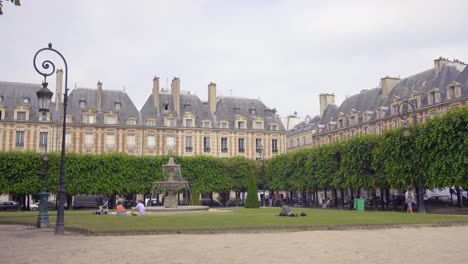 People-Sitting-On-Lawn-Grass-Around-A-Fountain-In-A-Public-Park