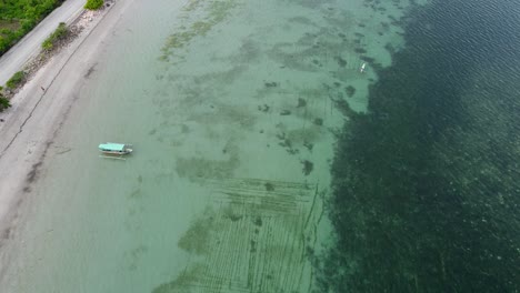 Aerial-flight-over-seaweed-farm-and-local-fishing-canoe-boats-in-turquoise-waters-of-coral-triangle-on-stunning-remote-tropical-island