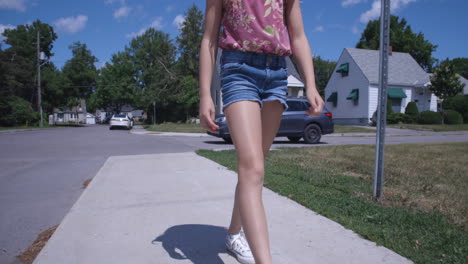 Young-blonde-girl-walking-along-sidewalk