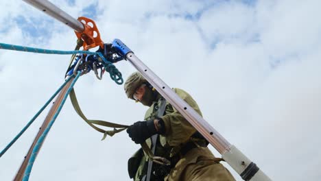 A-soldier-in-a-tunnel-unit-assembles-metal-rings-on-a-tripod-in-preparation-for-continuing-professional-work