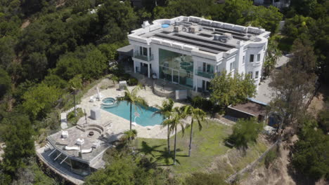 Aerial-of-multi-level-Hollywood-Hills-mansion-with-large-swimming-pool,-guest-quarters-and-solar-panels