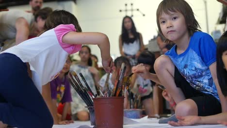 Kind-Wäscht-Pinsel-Und-Rennt-Aus-Dem-Rahmen,-Während-Andere-Kinder-Im-Hintergrund-Malen