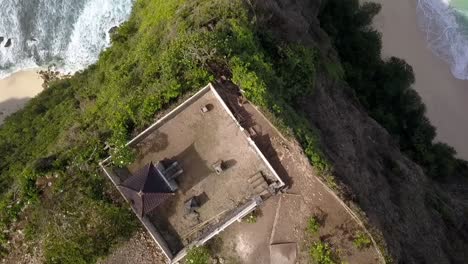 Breathtaking-aerial-view-flight-drone-camera-pointing-down-shot-of-temple-on-dangerous-cliff-edge-Kelingking-Beach-at-Nusa-Penida-in-Bali-Indonesia-Cinematic-nature-cliff-view-above-by-Philipp-Marnitz