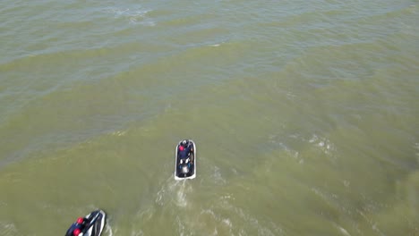 Aerial-footage-towards-a-man-in-the-water-and-two-Jet-Skis-making-a-maneuver-then-the-ocean