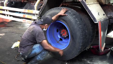 truck-mechanic-using-iron-stick-as-leverage-for-put-in-wheel