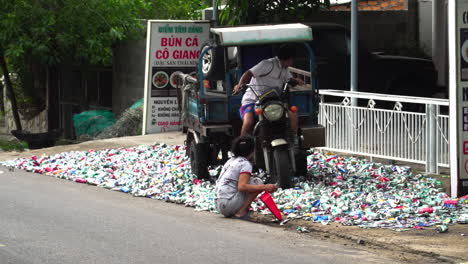 Southeast-Asian-in-Vietnam-flattening-metal-cans-for-recycling-with-motor-vehicle
