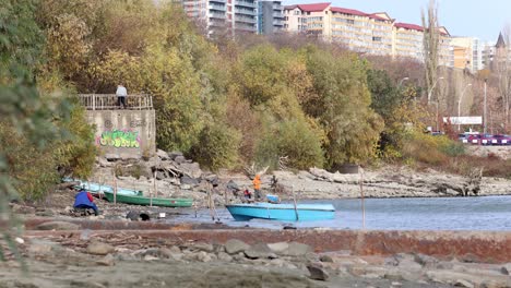 Fisherman-Catching-Fish-With-A-Fishing-Rod-By-The-Bank-Of-Danube-River-In-Galati,-Romania-On-A-Windy-Day