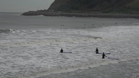 Surfers-waiting-for-some-good-waves-to-come-in-Scarborough,-Yorkshire,-UK