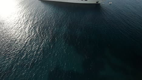 Aerial-revealing-shot-of-the-Dilbar,-a-mega-yacht-of-the-Russian-billionaire-oligarch-Alisher-Usmanov-anchoring-on-the-emerald-waters-near-Porto-Cervo-in-Sardinia