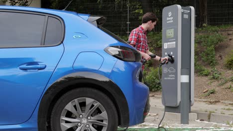 Joven-Enchufando-Un-Coche-Peugeot-Eléctrico-A-La-Estación-De-Carga-Energa-En-Polonia