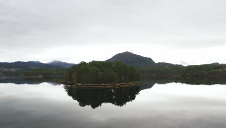 Kleine-Insel-Mit-Grünen-Bäumen-Inmitten-Eines-Sees,-Der-Sich-Im-Wasser-Spiegelt,-Norwegen