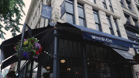 Water-st-cafe-front-entrance-corner-tarp-canopy-medium-wide-angle-panning-down-onto-front-doors-patio-on-sunny-day-downtown-vancouver-BC