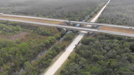 Puente-De-La-Carretera-Sobre-El-Canal-Camino-De-Tierra-Paso-Elevado-Autopista-De-Los-Everglades-Florida-Inclinación-Aérea-Del-Dron