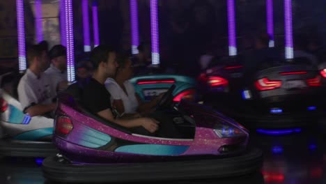 Crowd-of-people-having-fun-driving-bumper-cars-with-neon-lights-at-Balvarian-festival-at-Stuttgart,-Germany,-Europe-at-sunset,-panning-view-angle