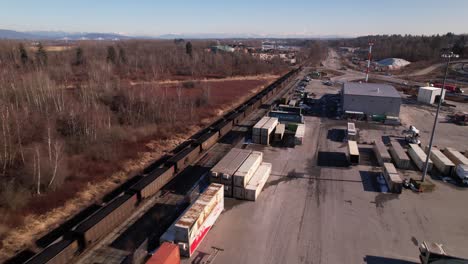Aerial-view-of-cargo-train-passing-close-to-containers-dock-of-Vancouver-shipping-terminal-in-Canada