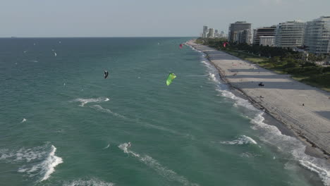 Following-aerial-of-kite-surfers-enjoying-sunny-afternoon,-Miami-Beach