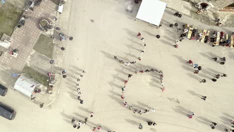 Drone-shot-over-crowds-of-Bulgarians-celebrating-festival-with-traditional-horo-dancing-in-village-square