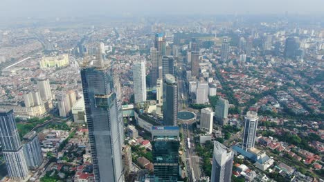 Drone-flying-over-skyscrapers-of-financial-district-and-Hotel-Indonesia-roundabout-in-background,-Jakarta