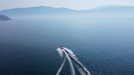 Speed-boat-driving-fast-in-curves-over-deep,-blue-Okanagan-Lake-on-a-hot-summer-day-in-Canada