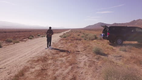 Young-Man-Prepares-to-Launch-a-Consumer-Drone-on-Sandy-Desert-Road-Path