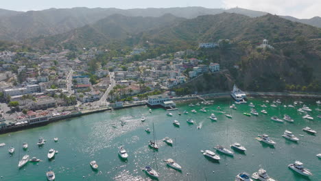 Wunderschöner-Hafen-Von-Avalon-Auf-Der-Insel-Catalina,-Gesehen-Von-Einer-Drohne,-Die-Mit-Angedockten-Booten-Und-Felsigem-Gelände-über-Die-Sonnige-Insel-Fliegt