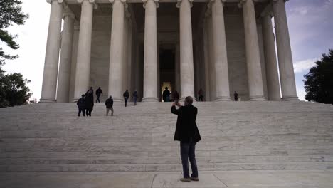 Walking-towards-Jefferson-Memorial,-Tourist-take-pictures-with-smartphone,-Washington-Landmark