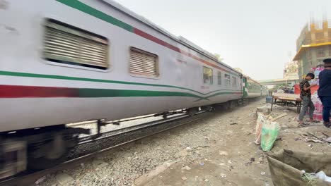 Passenger-train-with-a-diesel-engine-carrying-passengers-passing-through-the-busy-city-in-Dhaka,-Bangladesh-on-a-sunny-morning