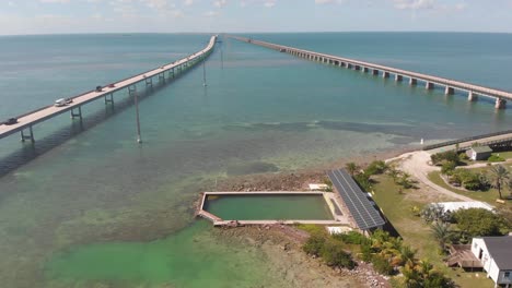 pigeon-key-florida-seven-mile-bridge-salt-water-pool-solar-panel-historic-clear-water-tropical-vacation-destination-aerial-drone-tilt-reveal