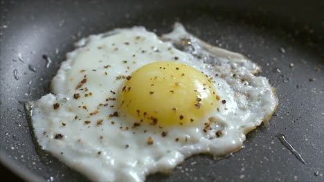 Nahaufnahmen-Eines-Gewürzten-Eies,-Das-In-Einer-Schwarzen,-Trockenen-Bratpfanne-Gebacken-Wird