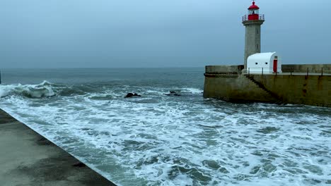 Riesige-Wellen,-Die-Im-Leuchtturm-Farolim-De-Felgueiras-Zusammenbrechen,-Mit-Menschen,-Die-Auf-Der-Seite-Gehen,-In-Der-Küstenstadt-Porto,-Portugal