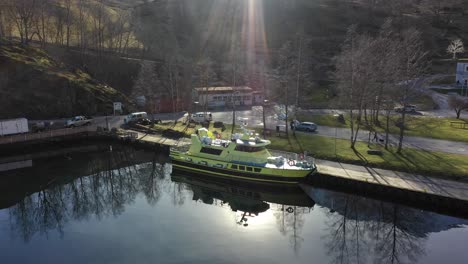 Ambulance-boat-named-Alden-is-alongside-in-port-of-Flam-during-beautiful-spring-sunrise---Slow-moving-aerial-wit-sunrays-and-sea-reflections