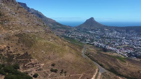 Drone-shot-of-Cape-Town---drone-is-reversing-near-Woodstock-Cave-at-Table-Mountain,-facing-Lions-Head