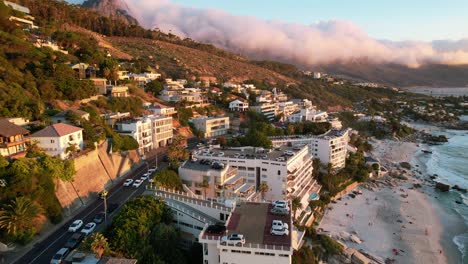 traffic-driving-at-sunset-above-Clifton-Beach-in-Cape-Town-during-summer,-aerial