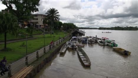 Varios-Barcos-Fluviales-Atracados-A-Lo-Largo-De-La-Orilla-De-Un-Gran-Río-En-Clima-Tropical
