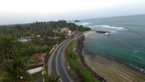 Aerial-FPV-shot-of-street-with-house-and-sea-in-the-side