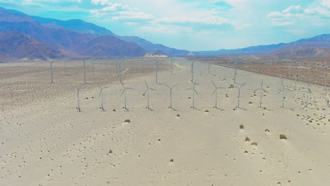 Aerial-sweeping-shot-of-wind-farm-in-Palm-Springs-desert-|-Mountains-in-background-|-Afternoon-lighting