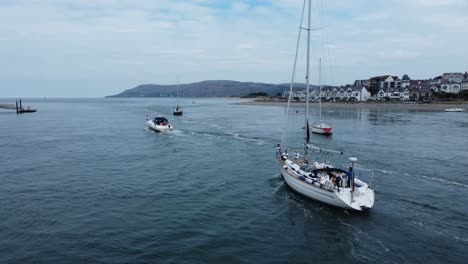 Aerial-view-following-luxury-yacht-travelling-along-scenic-river-estuary