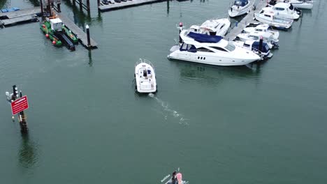 Aerial-view-above-small-motorboat-navigating-wealthy-waterfront-marina