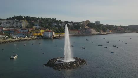 Aerial-view-around-a-Water-Fountain-from-ocean,-on-the-coast-of-Lisbon,-Portugal