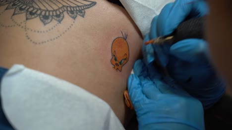 El-Tatuador-Está-Tatuando-El-Canario-Tweety-De-Looney-Tunes-En-La-Piel-De-Una-Mujer