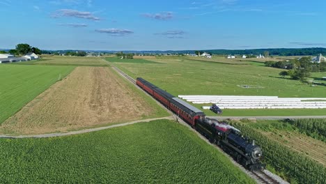 An-Aerial-View-of-an-Antique-Steam-Passenger-Train-Approaching-Blowing-Smoke-and-Steam-Traveling-Thru-Fertile-Corn-Fields-During-the-Golden-Hour-on-a-Sunny-Summer-Day