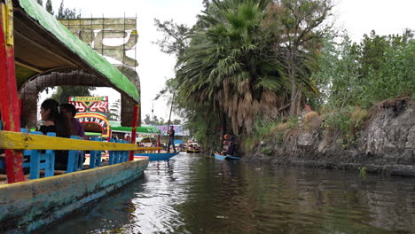 Steuerbordseitenansicht-Einer-Gondel,-Die-Touristen-Entlang-Der-Xochimilco-Kanäle-In-Richtung-Embarcadero-Nuevo-Nativitas-Befördert
