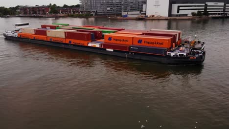 Mit-Intermodalen-Containern-Beladenes-Frachtschiff,-Das-über-Den-Trüben-Fluss-In-Den-Niederlanden-Fährt