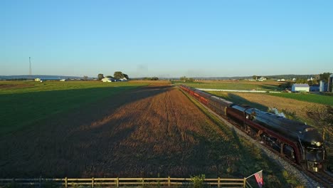 A-Drone-View-of-an-Antique-Steam-Passenger-Train-Blowing-Smoke-and-Steam-Traveling-Thru-Fertile-Corn-Fields-During-the-Golden-Hour-on-a-Sunny-Summer-Day