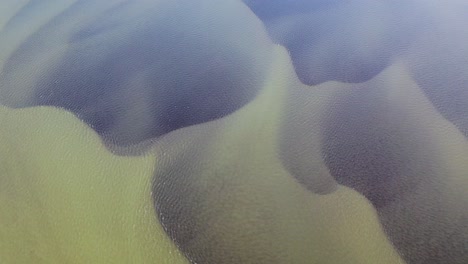 Aerial-top-down-shot-of-Olfusa-River-with-dark-pattern-underwater-during-sunny-day-on-iceland