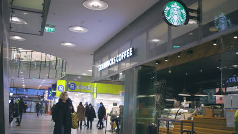 Slomo-Von-Menschen-Mit-Gesichtsmasken,-Die-Im-Einkaufszentrum-Helsinki-An-Starbucks-Vorbeigehen