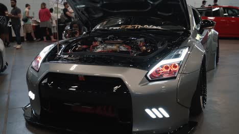 Bogenaufnahme-Eines-Silbernen-Nissan-GTR-Mit-Eingeschalteten-Lichtern-Auf-Der-Driven-Auto-Show