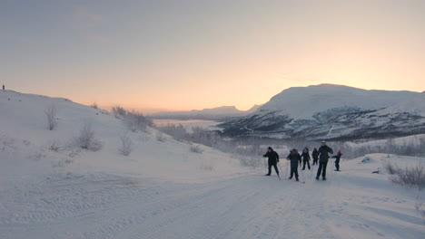 Gruppe-Von-Menschen,-Die-Mit-Langlaufskiern-Und-Schneeschuhen-In-Nordschweden-Einen-Hügel-Hinaufsteigen